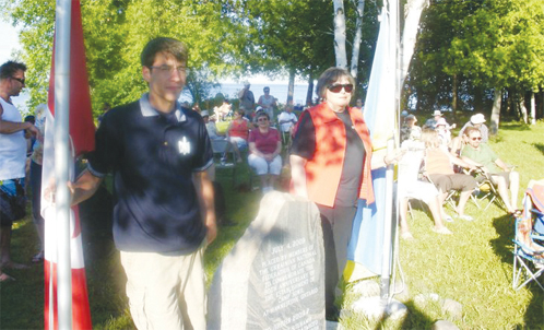 (L.-R.): UNF Toronto Branch President Slawko Borys & UWO Toronto Branch President Lydia Lelyk raising the flags at the start of the Ivana Kupalo programme by Camp “Sokil” 50th anniversary marker